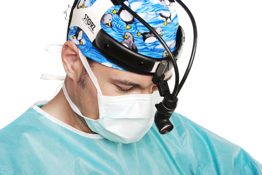 Dr. Günther mit OP-Maske und türkisem Kittel trägt ein chirurgisches Stirnlicht